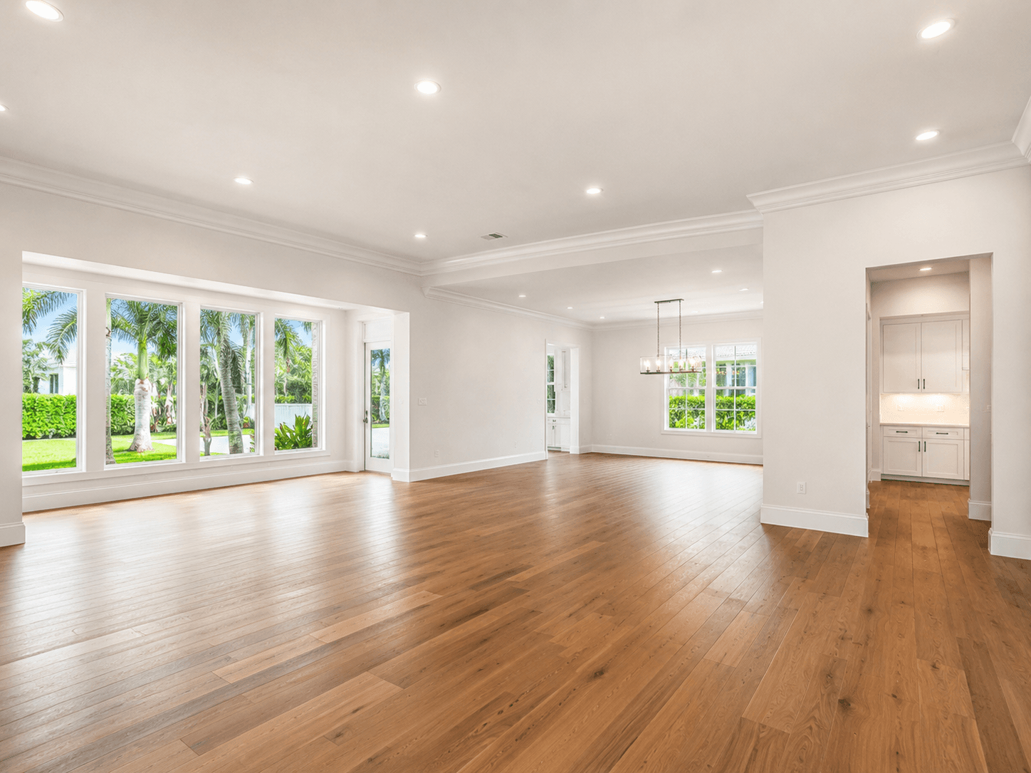 Bright open Florida room with wide-plank hardwood floors and French doors overlooking tropical garden by Benito Fine Carpentry